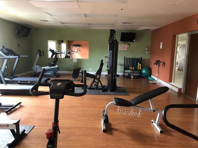 gym with a paneled ceiling and light wood-type flooring