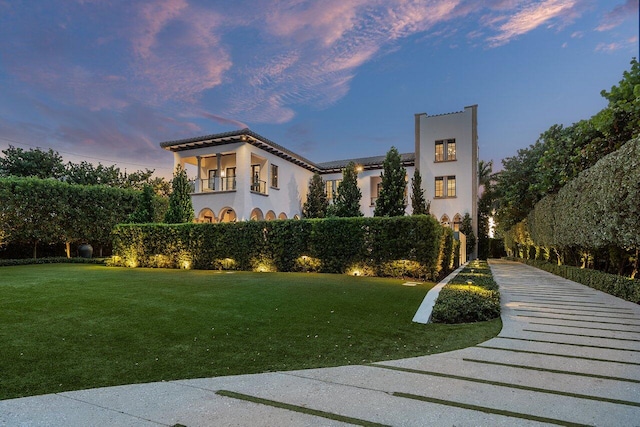 view of front of home with a balcony and a yard