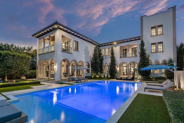 pool at dusk with a patio area