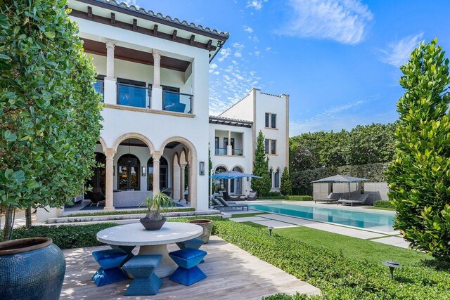 back of house with a balcony, an outdoor structure, and a patio