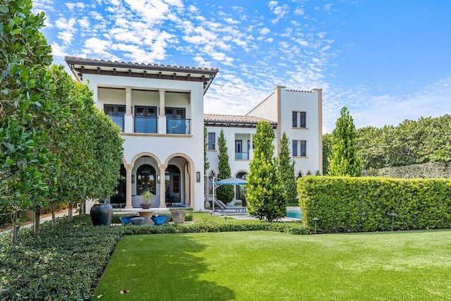 mediterranean / spanish house with a balcony, french doors, and a front yard