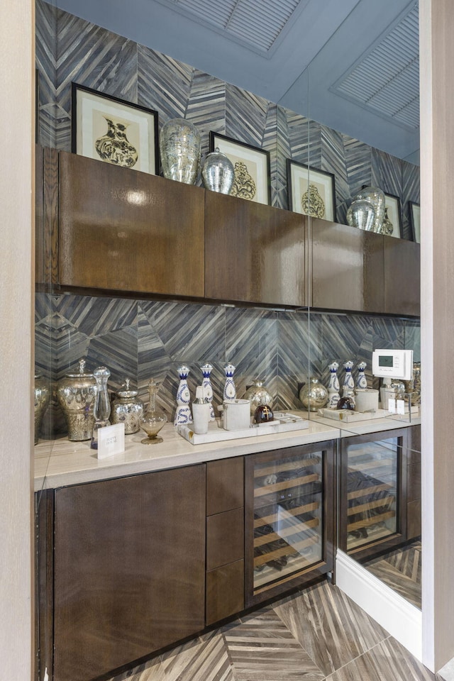 bar with parquet floors, beverage cooler, tasteful backsplash, and dark brown cabinets