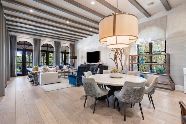 dining area featuring light wood-type flooring, french doors, and beamed ceiling