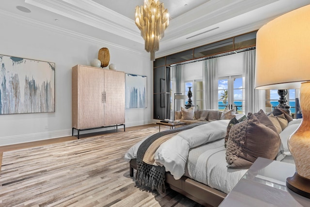 bedroom featuring a notable chandelier, a tray ceiling, ornamental molding, and light hardwood / wood-style flooring