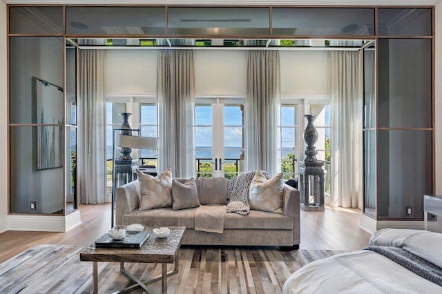 living room with a water view, light hardwood / wood-style floors, and french doors