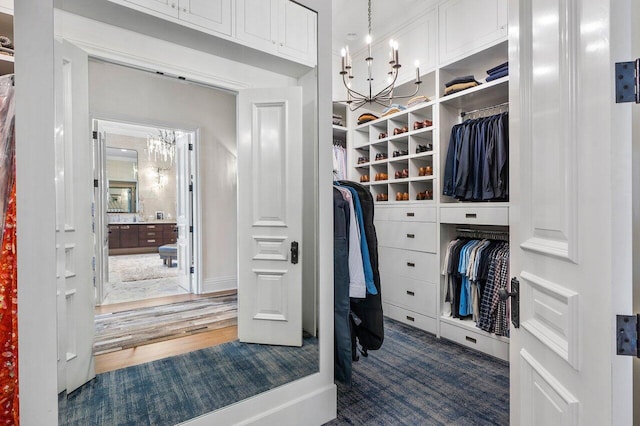 spacious closet featuring an inviting chandelier and dark wood-type flooring