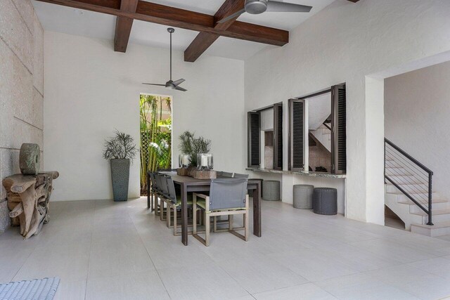 tiled dining room featuring a high ceiling, ceiling fan, and beamed ceiling