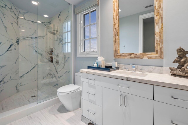 bathroom featuring vanity, a shower with shower door, and toilet