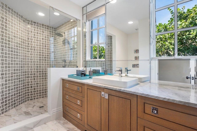 bathroom with tile floors, a tile shower, vanity, and a healthy amount of sunlight