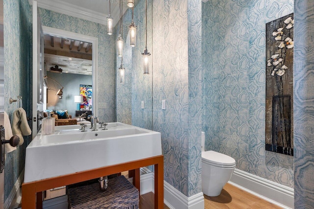 bathroom featuring toilet, crown molding, and hardwood / wood-style flooring