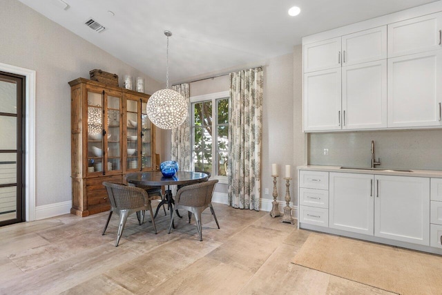 tiled dining space with a notable chandelier, sink, and lofted ceiling