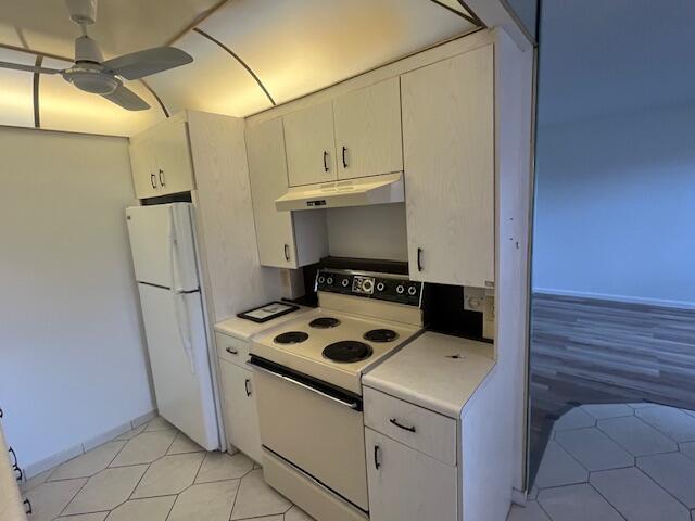 kitchen featuring ceiling fan, light tile patterned floors, white cabinets, and white appliances