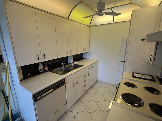 kitchen featuring light tile floors, white cabinets, dishwasher, and sink