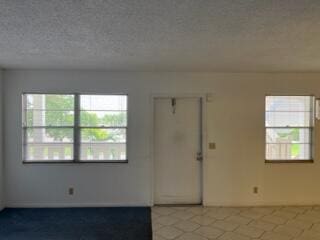 spare room with a textured ceiling and light tile floors