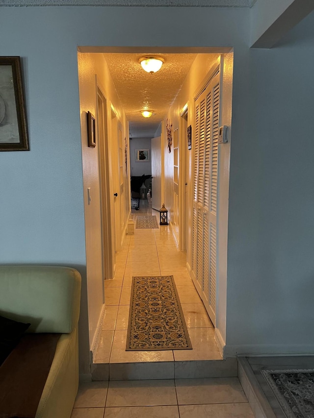 hall with light tile floors and a textured ceiling