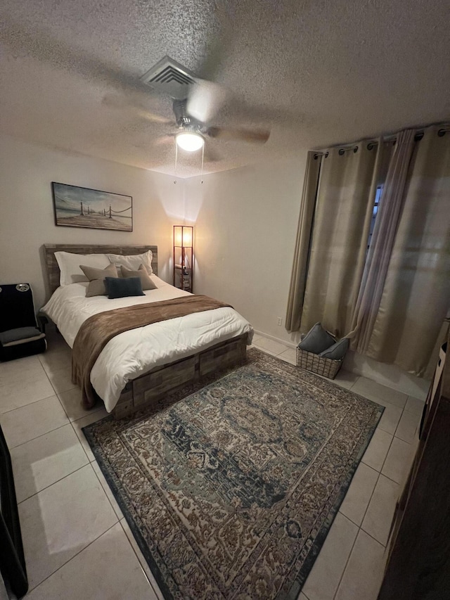 tiled bedroom with ceiling fan and a textured ceiling