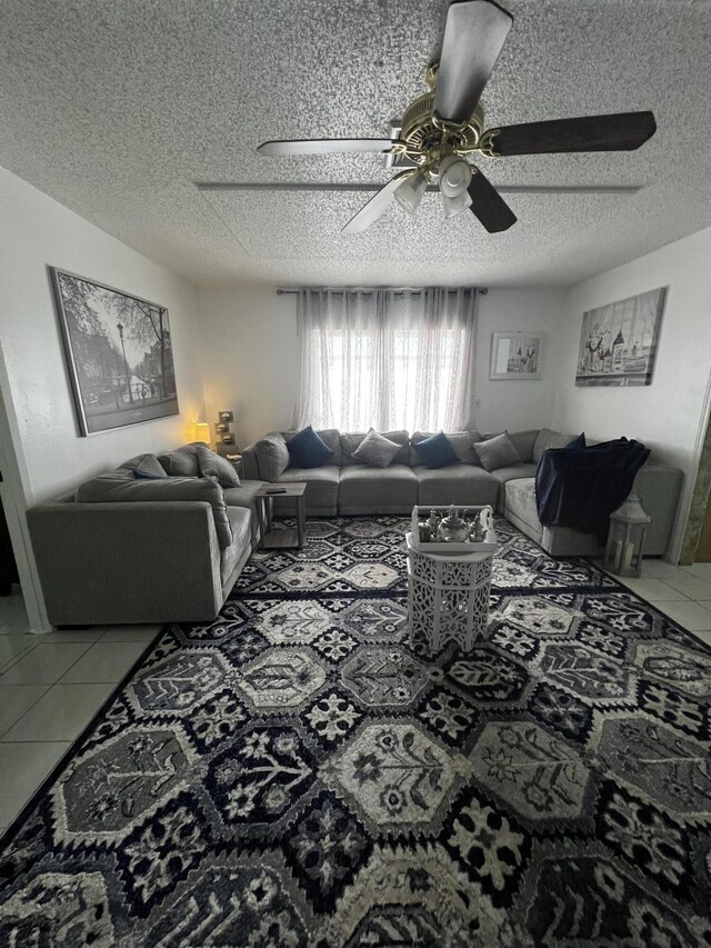 living room featuring light tile floors, a textured ceiling, and ceiling fan