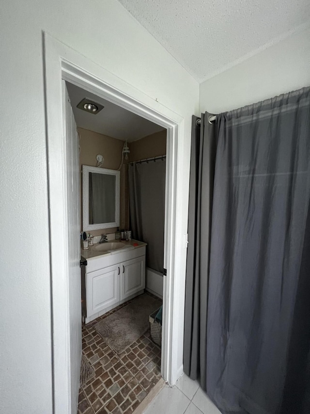 bathroom with a textured ceiling, tile floors, and vanity with extensive cabinet space