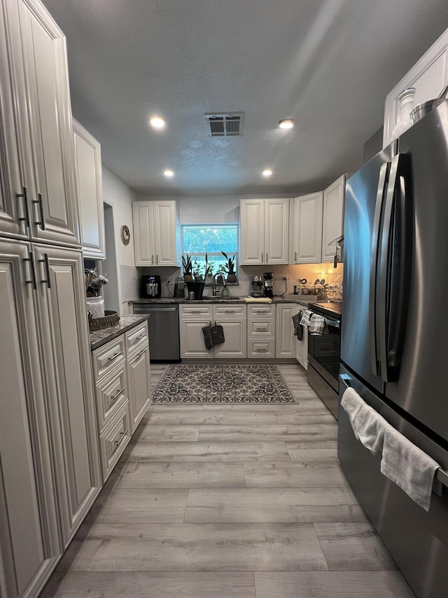 kitchen featuring light hardwood / wood-style floors, white cabinets, appliances with stainless steel finishes, and sink