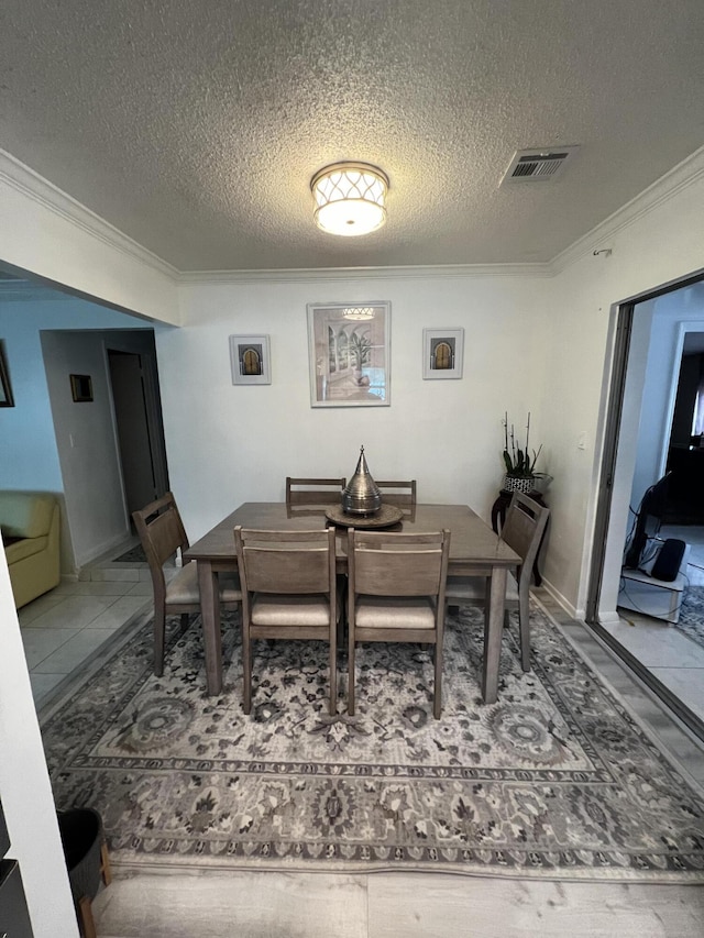 tiled dining area featuring ornamental molding and a textured ceiling