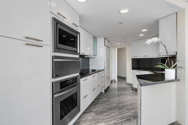 kitchen featuring gas cooktop, sink, stainless steel microwave, dark wood-type flooring, and white cabinetry