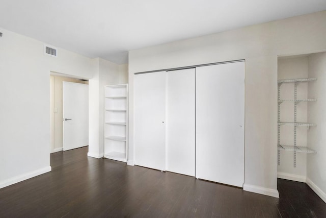 unfurnished bedroom with dark hardwood / wood-style floors and a closet