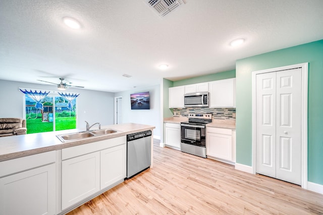 kitchen with ceiling fan, sink, appliances with stainless steel finishes, light hardwood / wood-style flooring, and white cabinetry