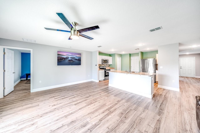 kitchen featuring light hardwood / wood-style floors, ceiling fan, appliances with stainless steel finishes, white cabinetry, and a kitchen island with sink