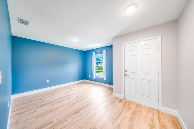 foyer entrance with a textured ceiling and light wood-type flooring