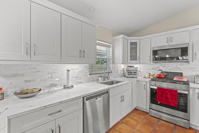 kitchen with white cabinetry, sink, lofted ceiling, and stainless steel appliances