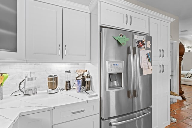 kitchen featuring stainless steel fridge, light stone counters, white cabinetry, and tasteful backsplash