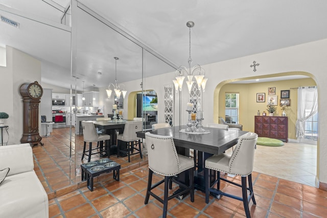 dining space with tile patterned floors, lofted ceiling, and a notable chandelier