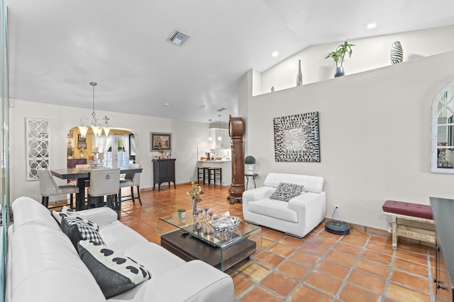 living room featuring tile patterned flooring, vaulted ceiling, and a chandelier