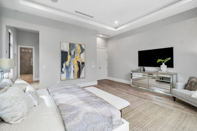 bedroom with a raised ceiling and light hardwood / wood-style flooring