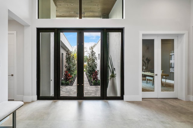 doorway to outside featuring french doors, light tile floors, and a high ceiling