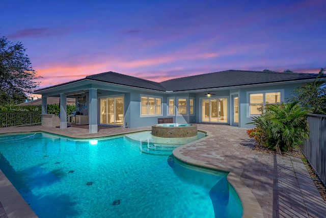 pool at dusk featuring a patio area, an in ground hot tub, and ceiling fan