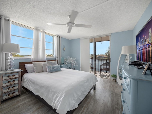 bedroom with ceiling fan, a textured ceiling, dark hardwood / wood-style floors, and access to exterior