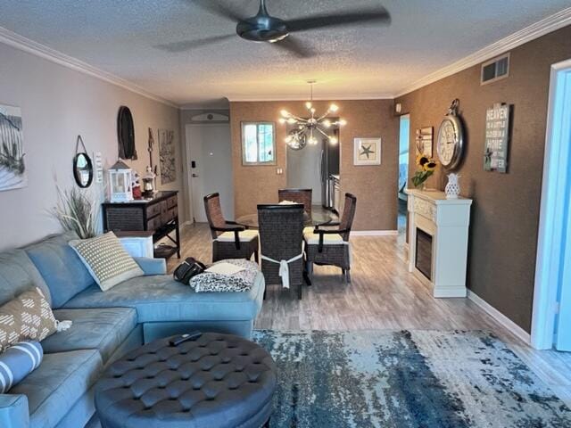 living room with ceiling fan with notable chandelier, crown molding, hardwood / wood-style floors, and a textured ceiling