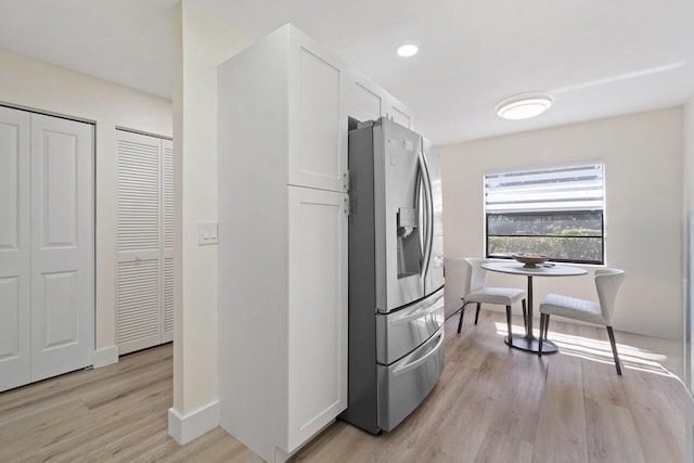 kitchen with white cabinetry, stainless steel fridge, and light hardwood / wood-style floors