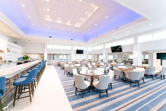 dining area featuring ornamental molding, a towering ceiling, light colored carpet, and a tray ceiling