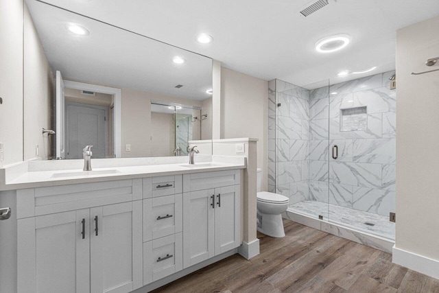 bathroom with vanity, hardwood / wood-style flooring, a shower with door, and toilet