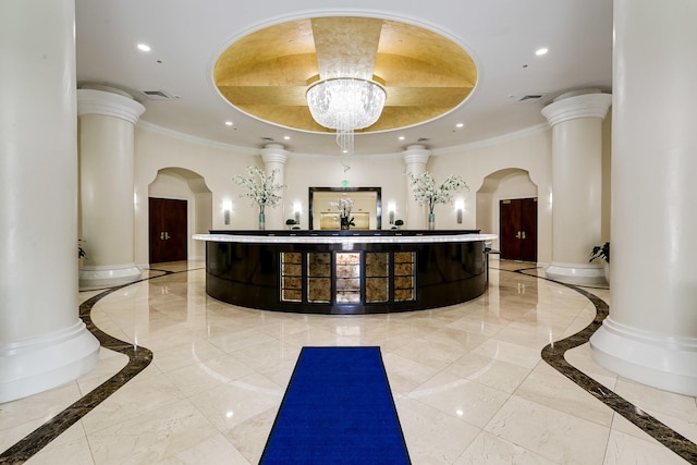 reception area with decorative columns and a notable chandelier