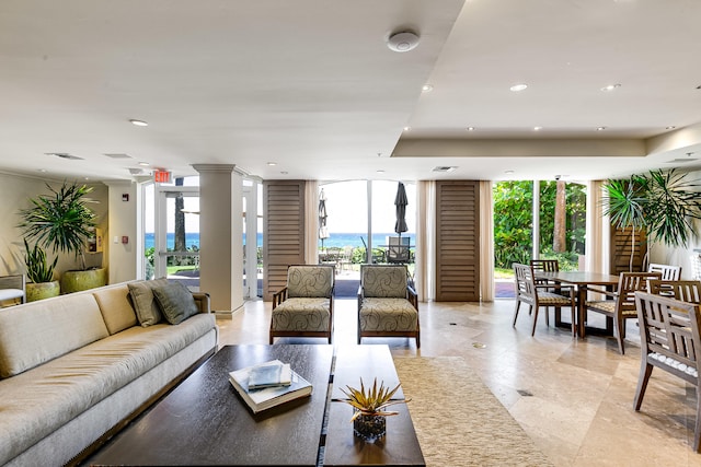 tiled living room with plenty of natural light, a water view, expansive windows, and a tray ceiling