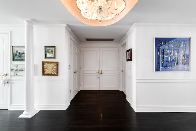 corridor featuring decorative columns, dark hardwood / wood-style floors, and crown molding