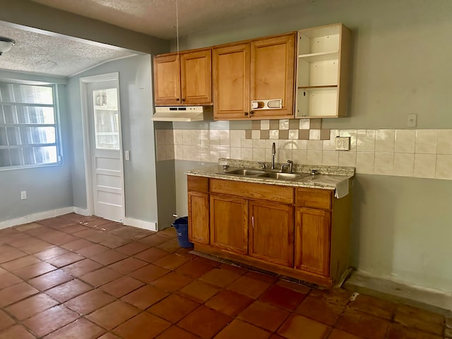 kitchen with decorative backsplash, sink, a textured ceiling, and dark tile patterned floors