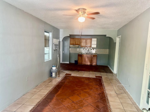 unfurnished living room featuring ceiling fan, light tile patterned floors, sink, and a textured ceiling