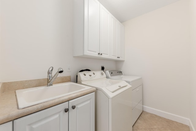 laundry area with sink, light tile floors, electric dryer hookup, washing machine and clothes dryer, and cabinets