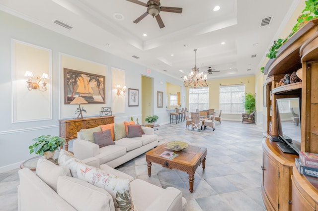 living room with light tile flooring, ornamental molding, ceiling fan with notable chandelier, and a tray ceiling