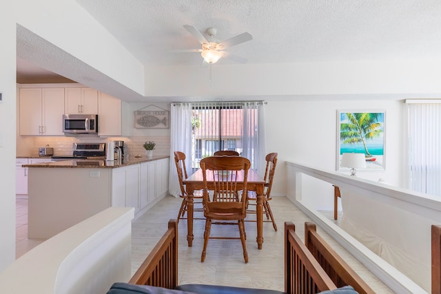 dining area with a textured ceiling, ceiling fan, and light wood-type flooring