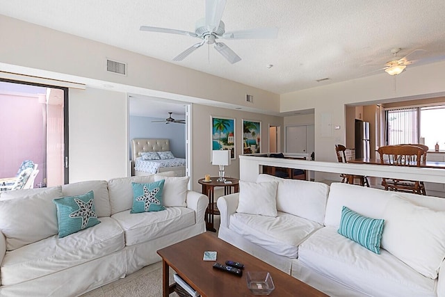 living room with light carpet, a textured ceiling, and ceiling fan